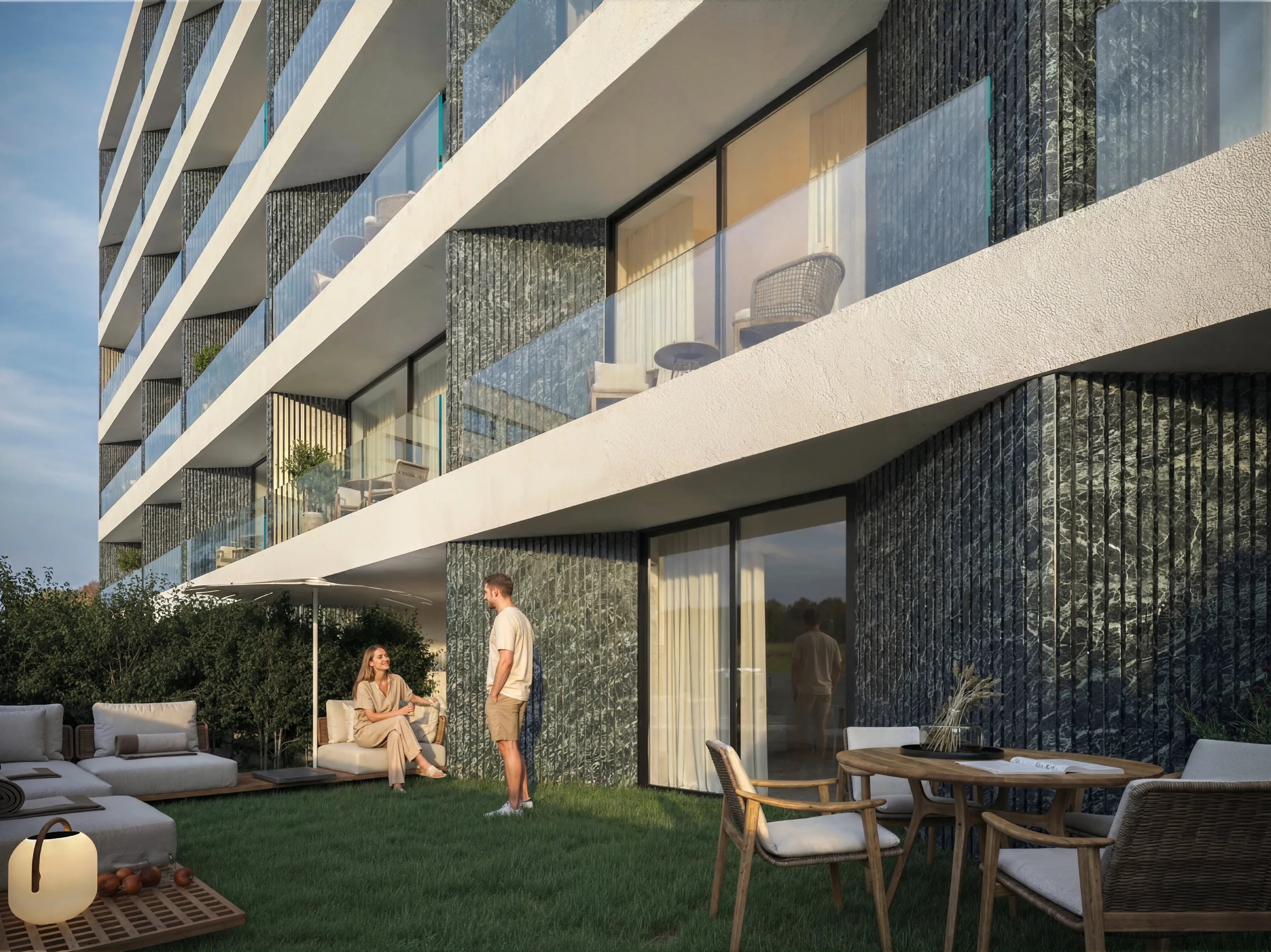 Blend.26 — jardim privado com fachada do empreendimento ao entardecer